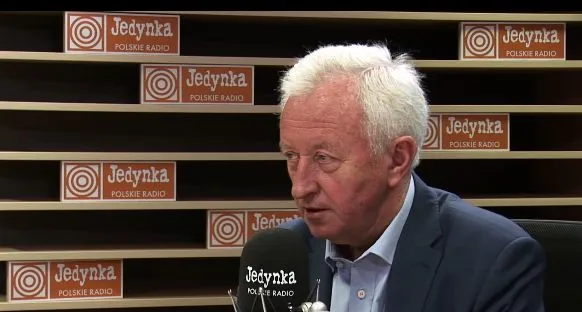 Mężczyzna w garniturze udziela wywiadu w studiu radiowym Jedynka Polskie Radio, przy mikrofonie.