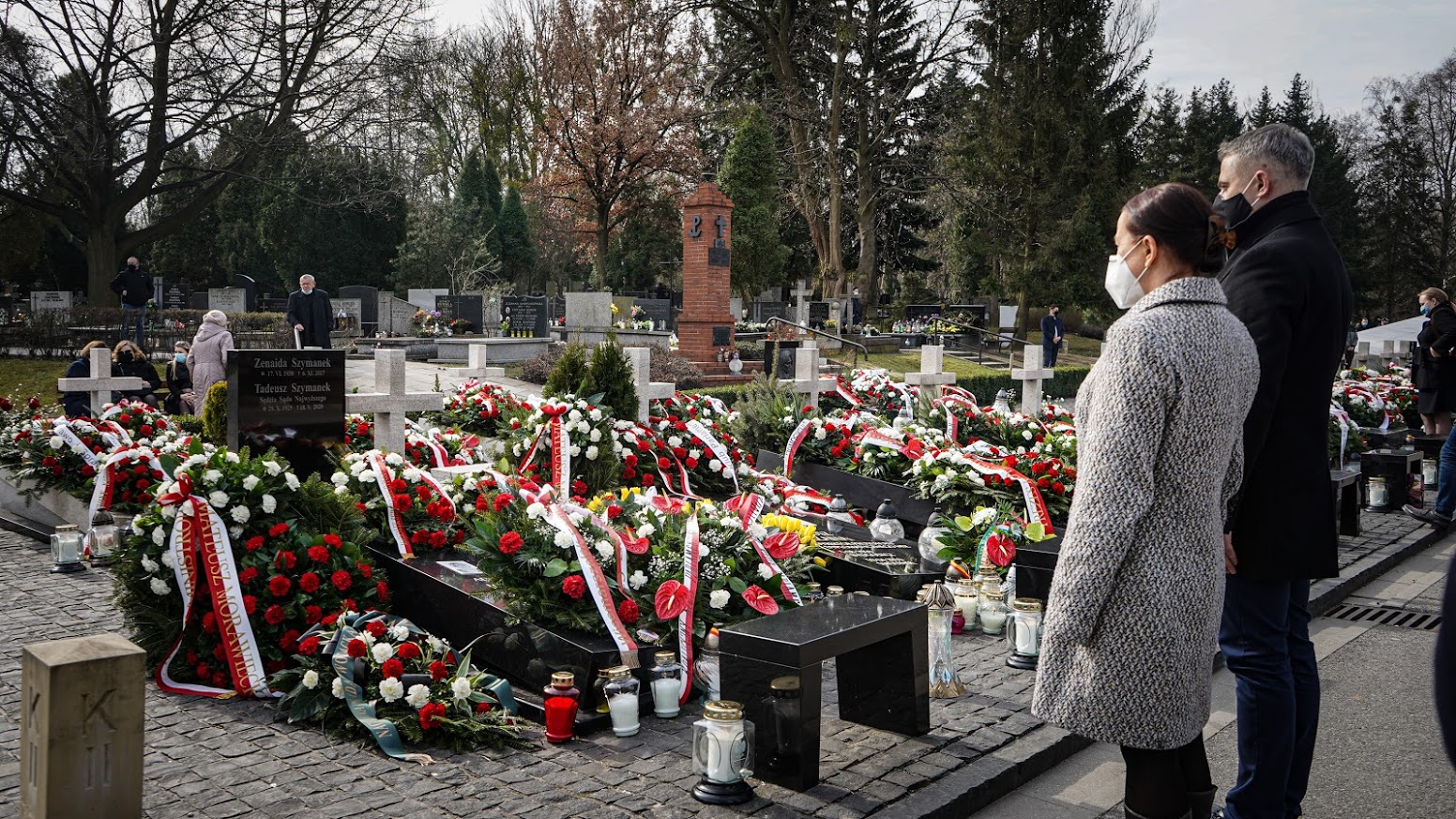Na cmentarzu upamiętniającym ofiary katastrofy smoleńskiej widoczne są liczne wieńce, kwiaty i znicze, a odwiedzający w maskach składają hołd z okazji 11. rocznicy tragedii.