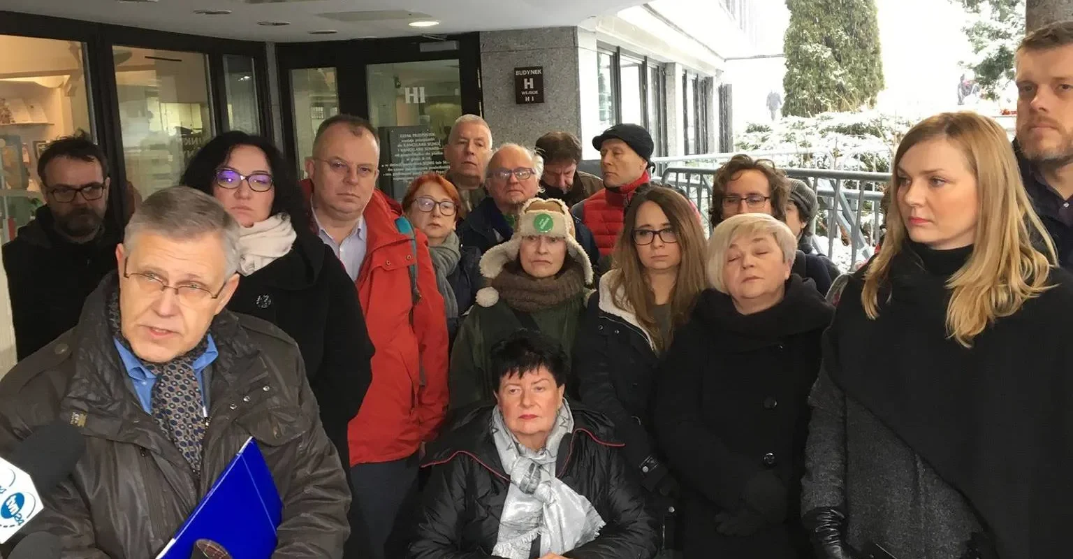 Grupa osób zgromadzona na zewnątrz budynku przed wejściem, podczas konferencji prasowej dotyczącej obywatelskiej inicjatywy ustawodawczej w sprawie świeckiego państwa.