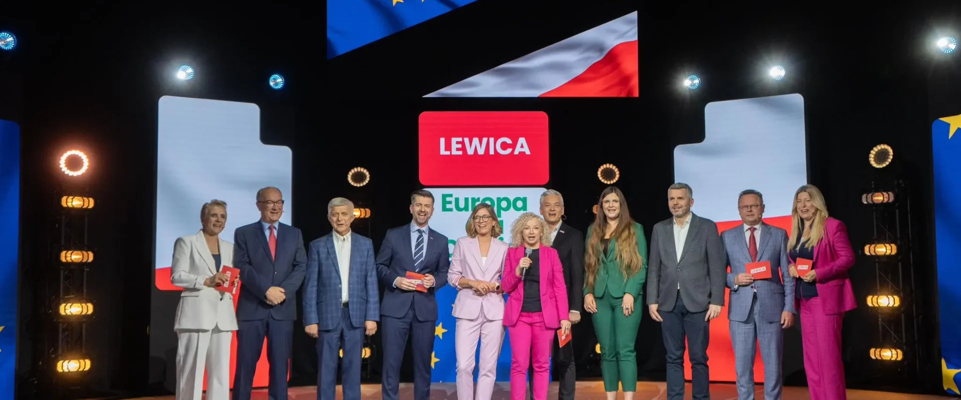 Grupa osób w eleganckich strojach stoi na scenie podczas prezentacji programu wyborczego „Europa dla Ciebie”, przed ekranami z napisem Lewica Europa i flagami UE oraz Polski w tle.