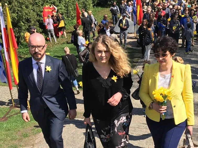 Trzech przedstawicieli SLD spaceruje wśród tłumu podczas niezależnych obchodów rocznicy Powstania w Getcie Warszawskim, trzymając żółte kwiaty i nosząc żółte przypinki.