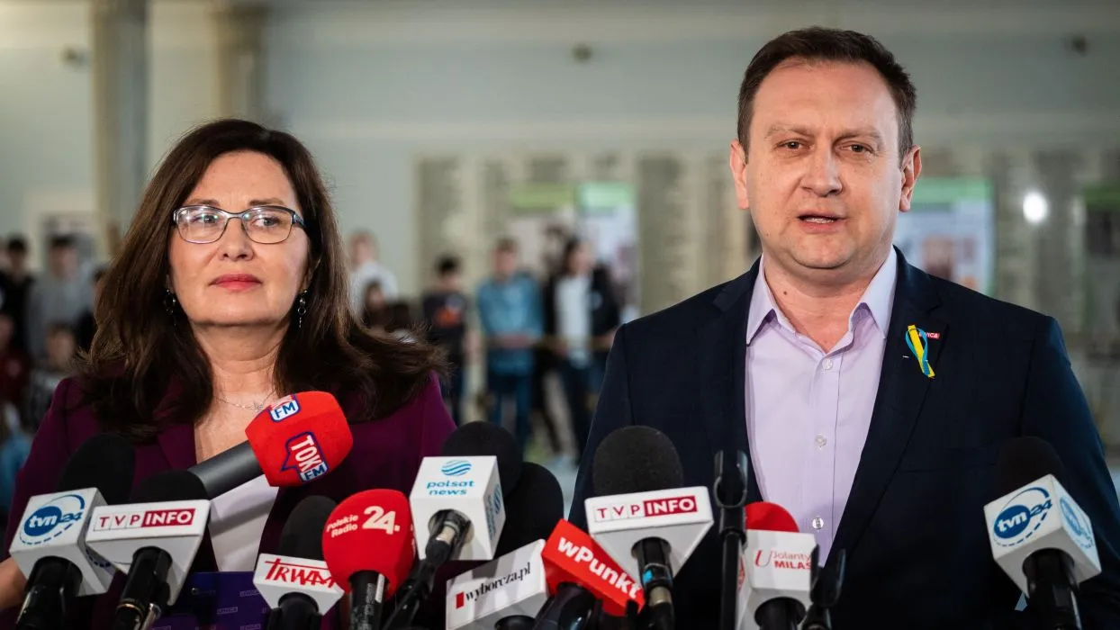 Dwójka polityków stoi przed mikrofonami podczas konferencji prasowej.