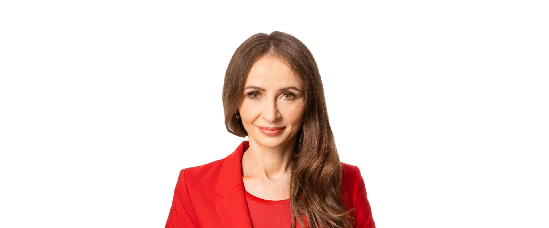 Portret uśmiechniętej kobiety z długimi brązowymi włosami, ubranej w czerwony blazer, na białym tle.