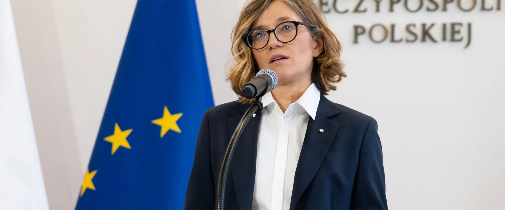 Kobieta w garniturze i okularach przemawia z mównicy, na tle flagi Unii Europejskiej i napisu Senat Rzeczypospolitej Polskiej, odnosząc się do planu pokojowego dla Ukrainy.