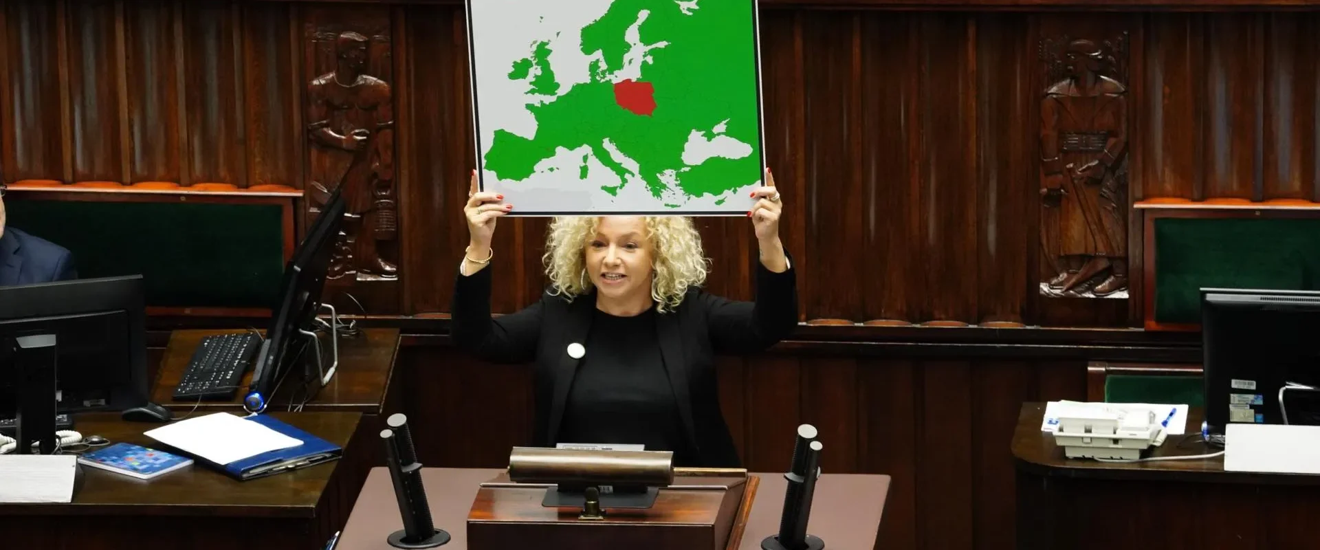 Kobieta w sejmowej sali plenarnej unosi nad głową planszę z mapą Europy, na której Polska została zaznaczona na czerwono, symbolizując sprzeciw wobec kompromisu aborcyjnego i referendum.