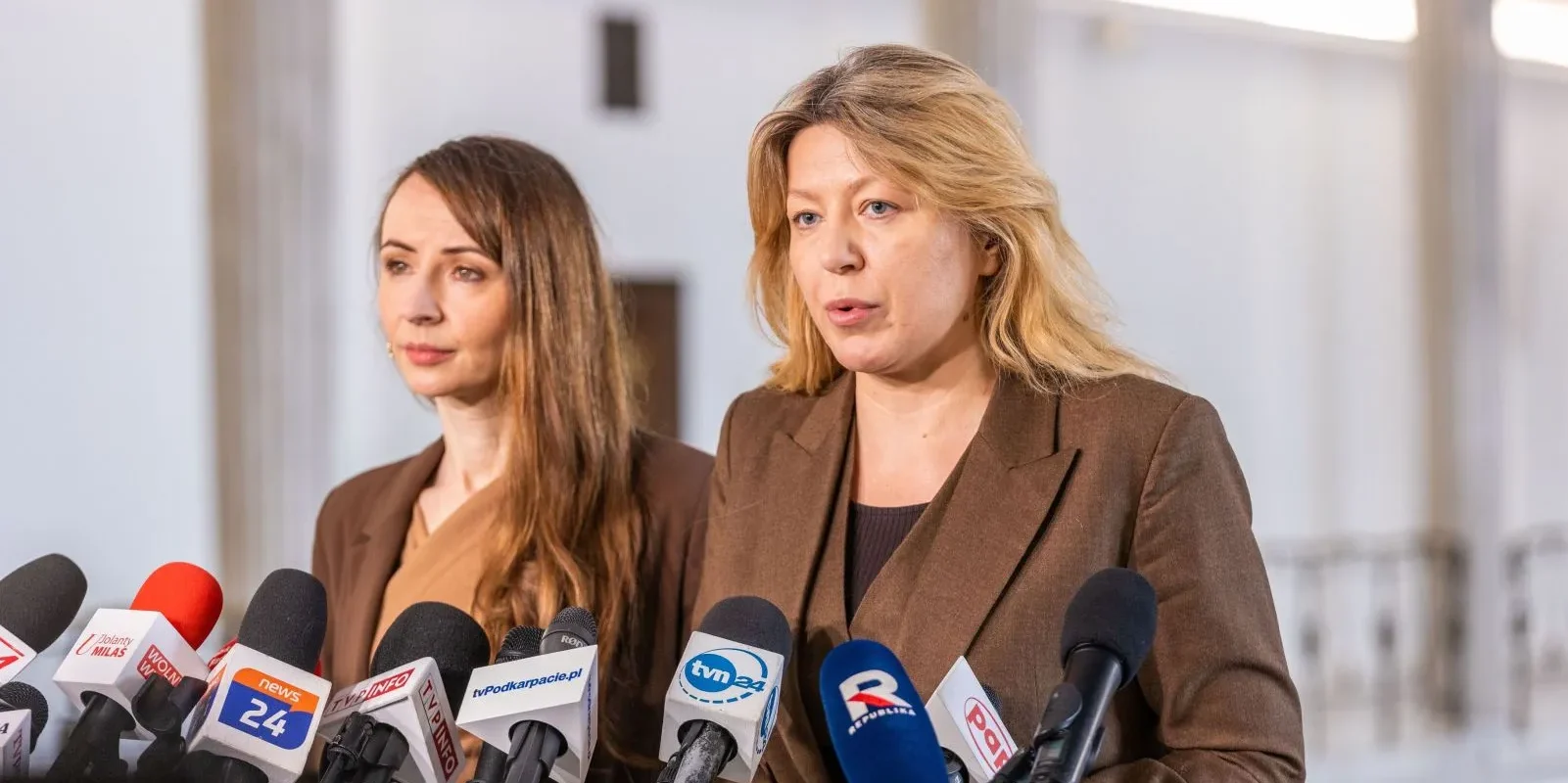 Dwie kobiety prowadzą konferencję prasową z okazji Dnia Walki z Depresją, otoczone licznymi mikrofonami mediów, omawiające postulat ustawy o zawodzie psychologa.