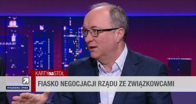 Mężczyzna w garniturze i okularach prowadzi rozmowę w studiu telewizyjnym; na dole ekranu widoczny jest pasek z nagłówkiem o fiasku negocjacji rządu ze związkowcami.