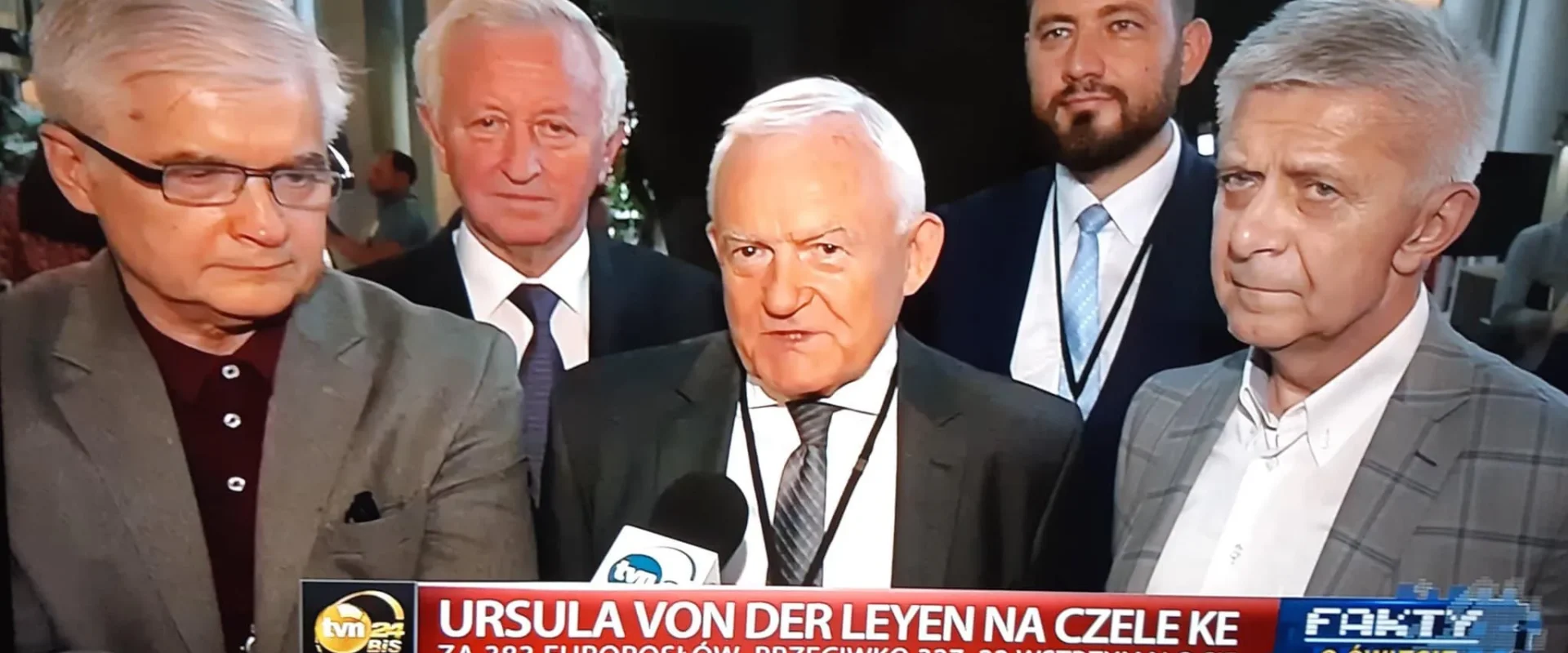 Grupa mężczyzn w garniturach udziela wywiadu telewizyjnego przed kamerą podczas konferencji prasowej.