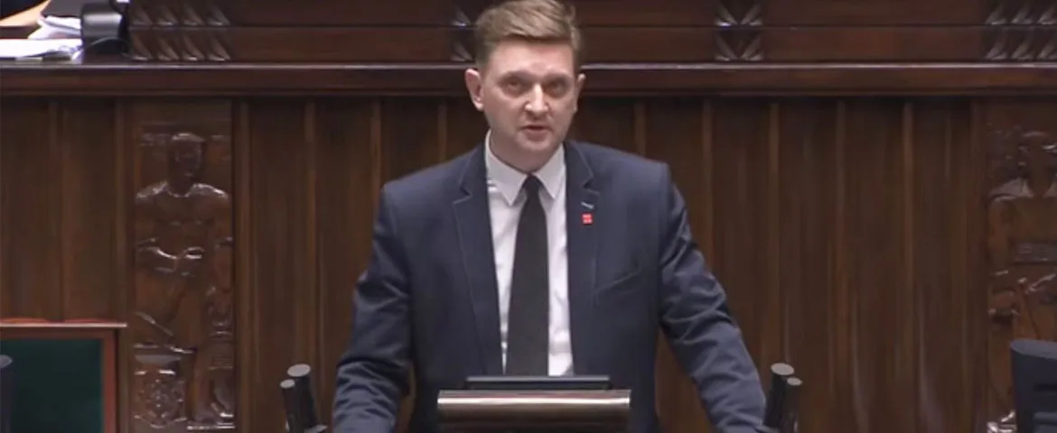 Mężczyzna w garniturze stoi przy mównicy w Sejmie podczas prezentacji obywatelskiego projektu ustawy dotyczącego emerytur mundurowych.