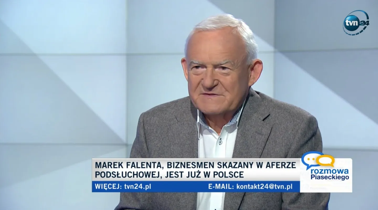 Mężczyzna w szarym garniturze siedzi w studiu telewizyjnym TVN24, a na dole ekranu widnieje informacyjny pasek o aferze podsłuchowej i jej potencjalnym wpływie na politykę.