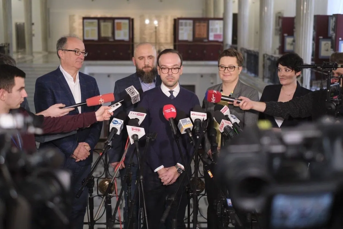 Grupa polityków podczas konferencji prasowej, jeden z nich przemawia do mikrofonów otoczony reporterami, wyrażając poparcie dla obywatelskiego projektu „Szczepimy bo myślimy”.