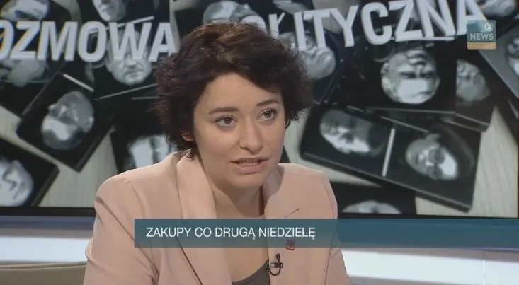Kobieta rozmawiająca w studiu telewizyjnym podczas programu „Rozmowa polityczna”, z napisem na pasku „Zakupy co drugą niedzielę”.