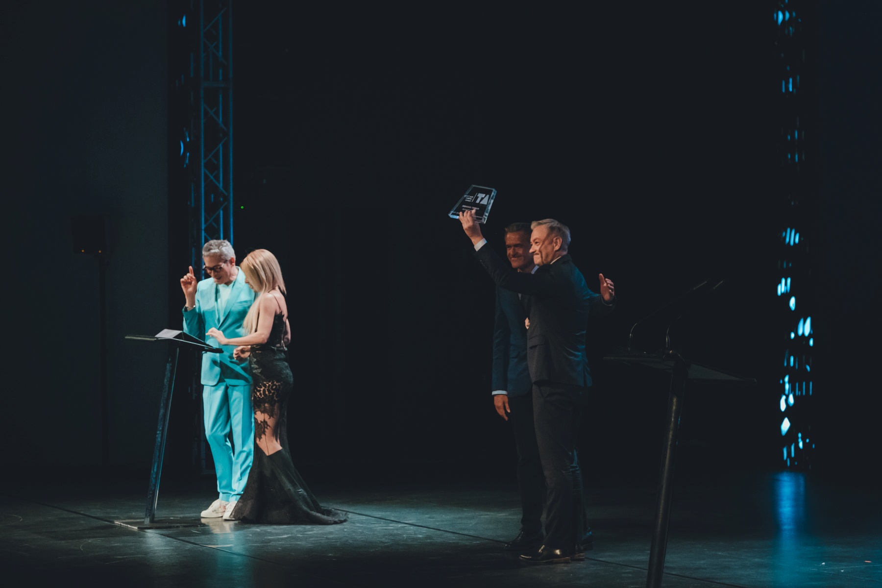 Na zdjęciu widoczna jest scena z wydarzenia, na której prowadzący i laureaci odbierają wyróżnienia, a publiczność może podziwiać atmosferę ceremonii.