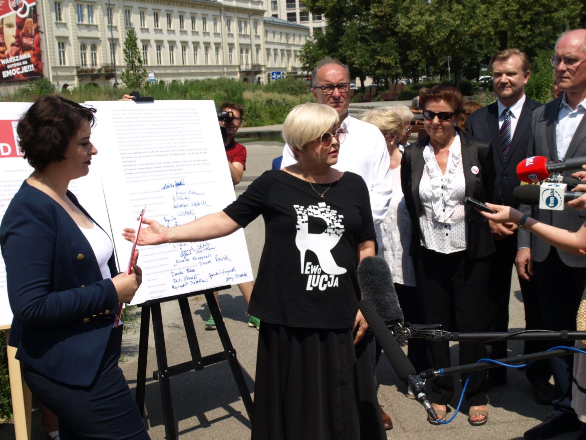 Grupa polityków i dziennikarzy na konferencji prasowej Lewicy Razem (SLD) przed tablicą z podpisami.