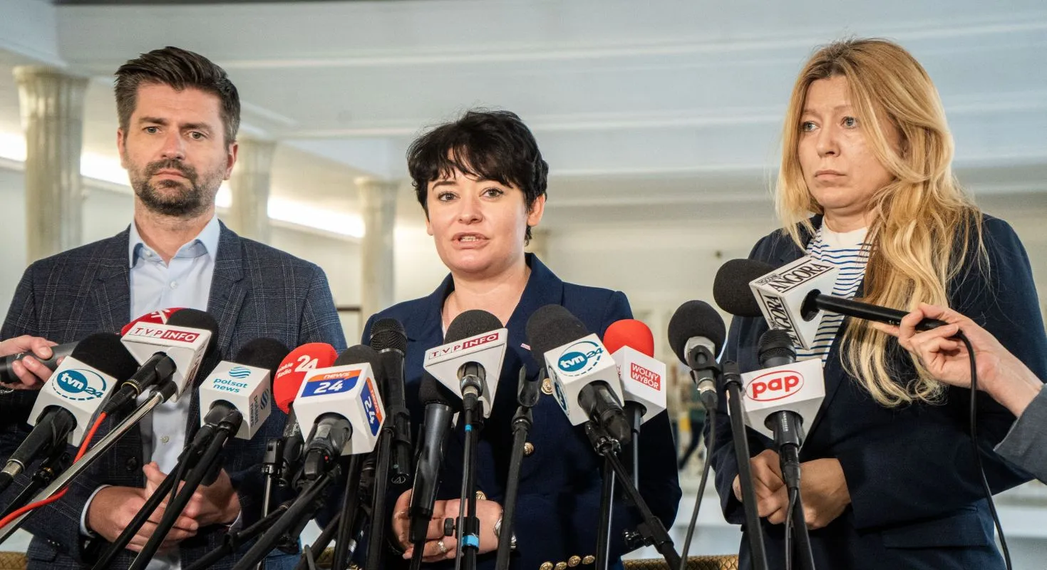 Zdjęcie przedstawia trójkę ludzi stojących za mikrofonami podczas konferencji prasowej.