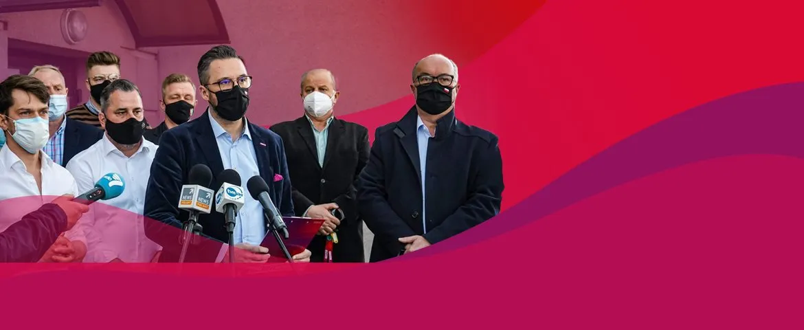 Grupa parlamentarzystów wraz z dziennikarzami podczas konferencji prasowej w Żurominie, przy stojących mikrofonach, wszyscy w maseczkach.