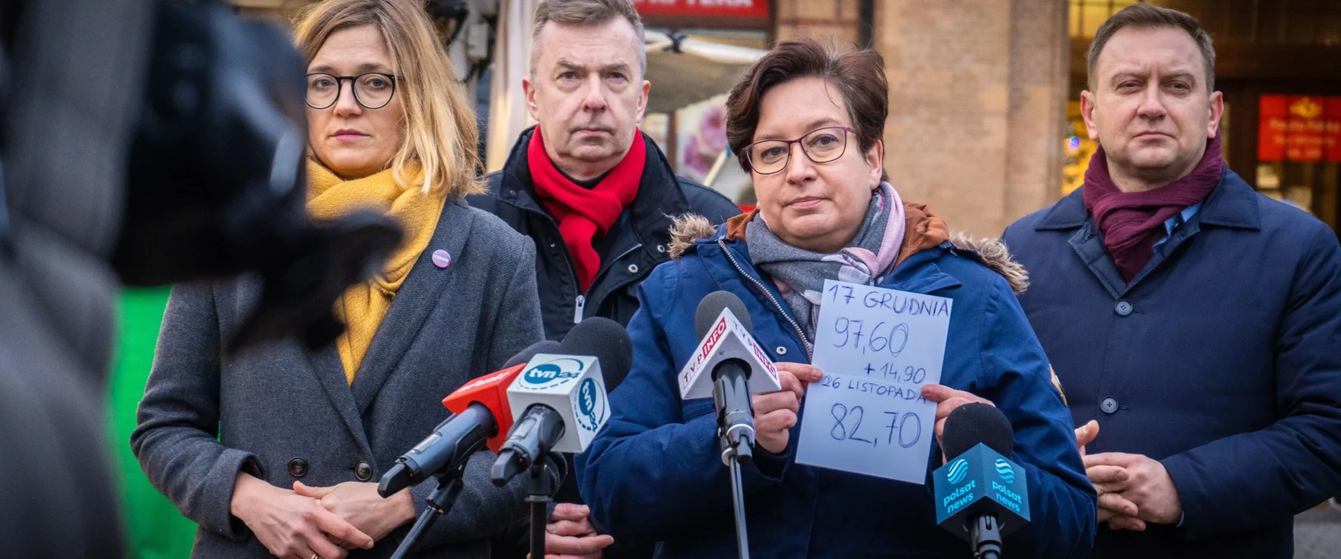Na zdjęciu przedstawiono konferencję prasową, na której cztery osoby dyskutują na temat danych ekonomicznych, trzymając kartkę z informacjami.