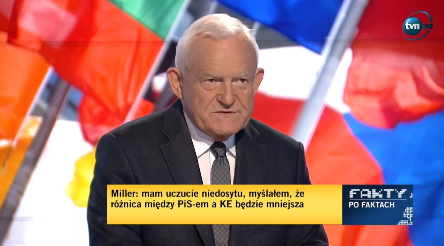 Mężczyzna w czarnym garniturze przed studiem telewizyjnym z kolorowymi flagami w tle, a na dole ekranu żółty pasek z cytatem i logo programu Fakty po Faktach.