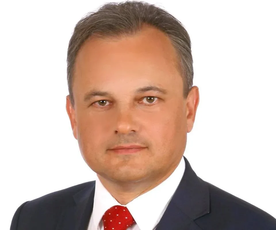 Portret mężczyzny w garniturze i czerwonym krawacie na białym tle.