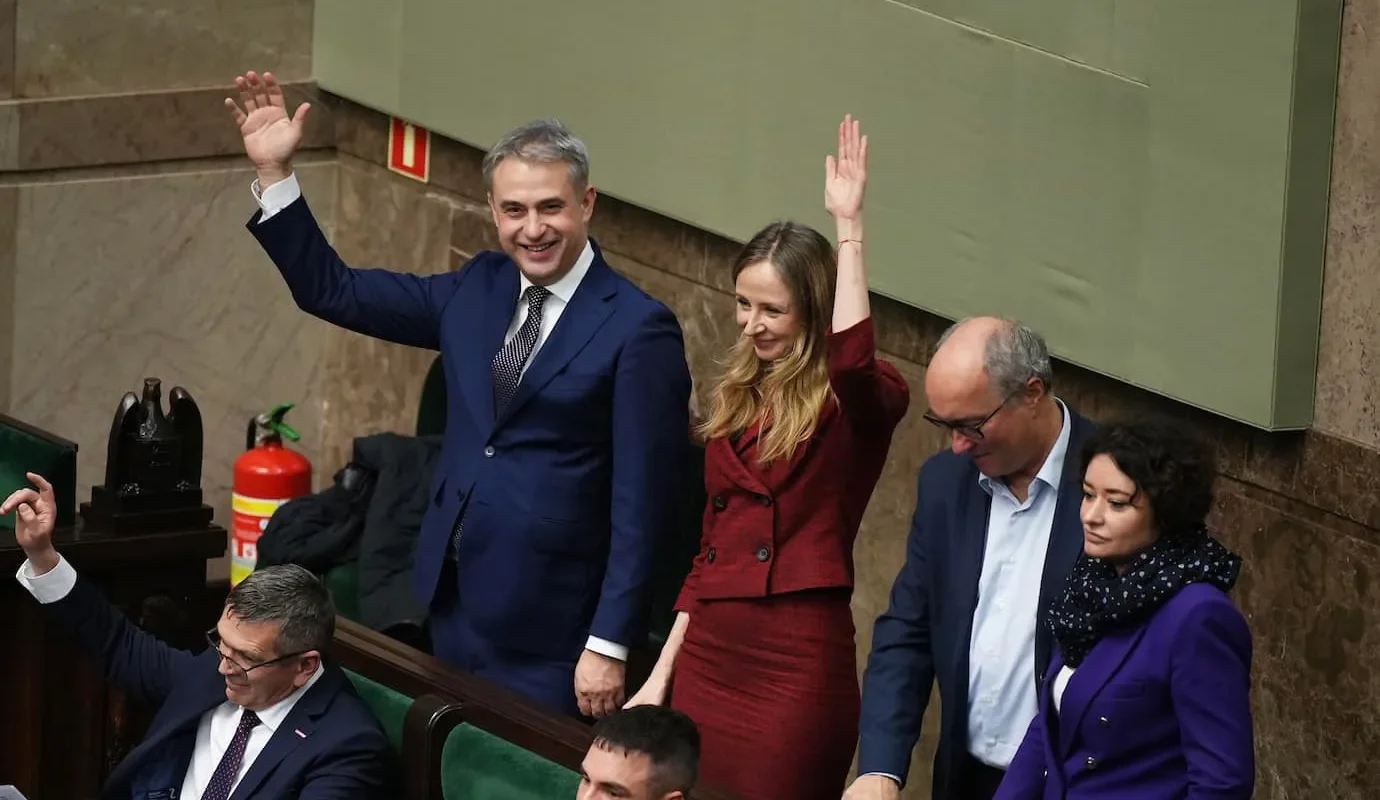 Grupa polityków na sali plenarnej Sejmu unosi ręce na znak poparcia dla projektów dotyczących Wolnej Wigilii i wydłużenia urlopów macierzyńskich.