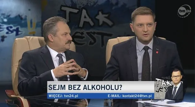 Dwóch mężczyzn w garniturach prowadzi dyskusję w studio telewizyjnym, z napisem „SEJM BEZ ALKOHOLU?” i logiem stacji, dotyczącą zakazu alkoholu w Sejmie.