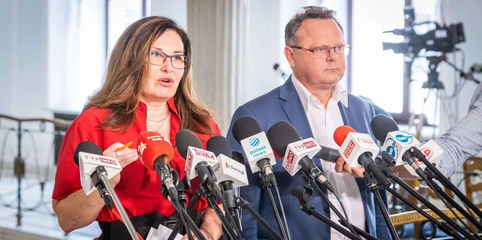 Dwoje polityków stoi przy zestawie mikrofonów na konferencji prasowej.