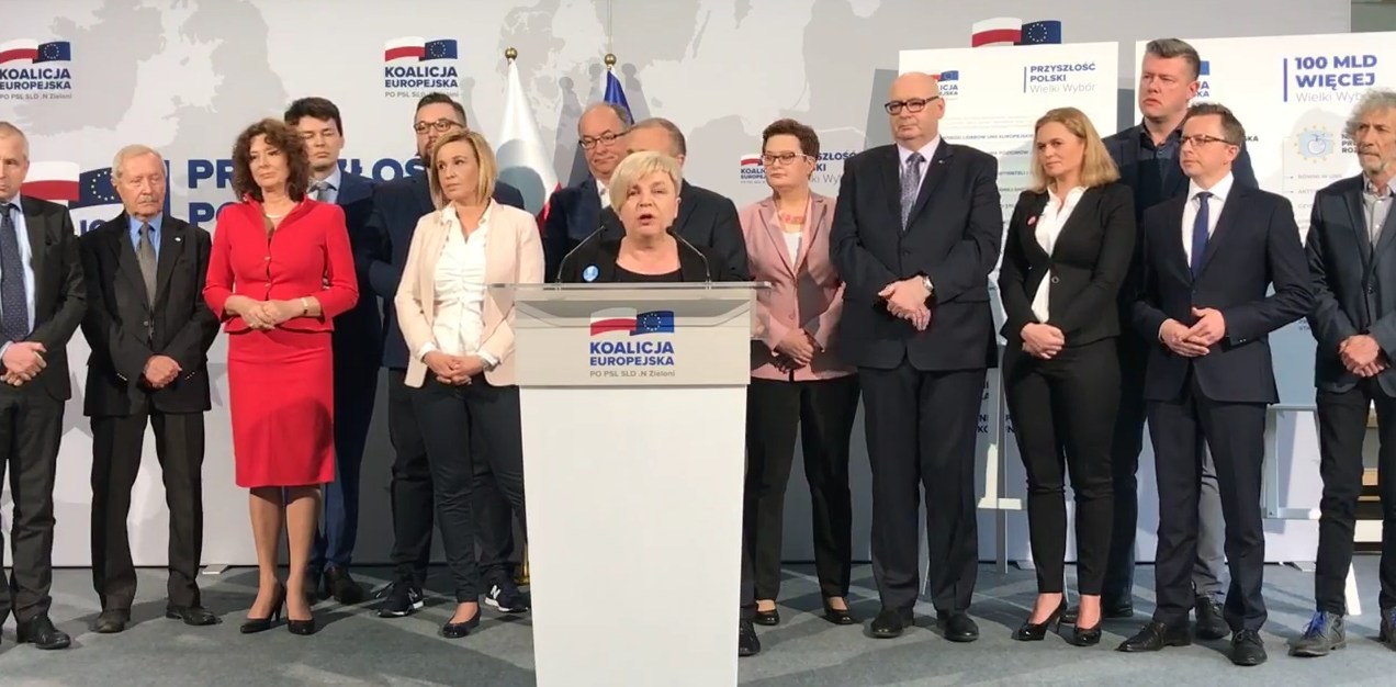 Grupa polityków stoi na scenie za podiumem z logotypem Koalicji Europejskiej podczas konferencji prasowej.