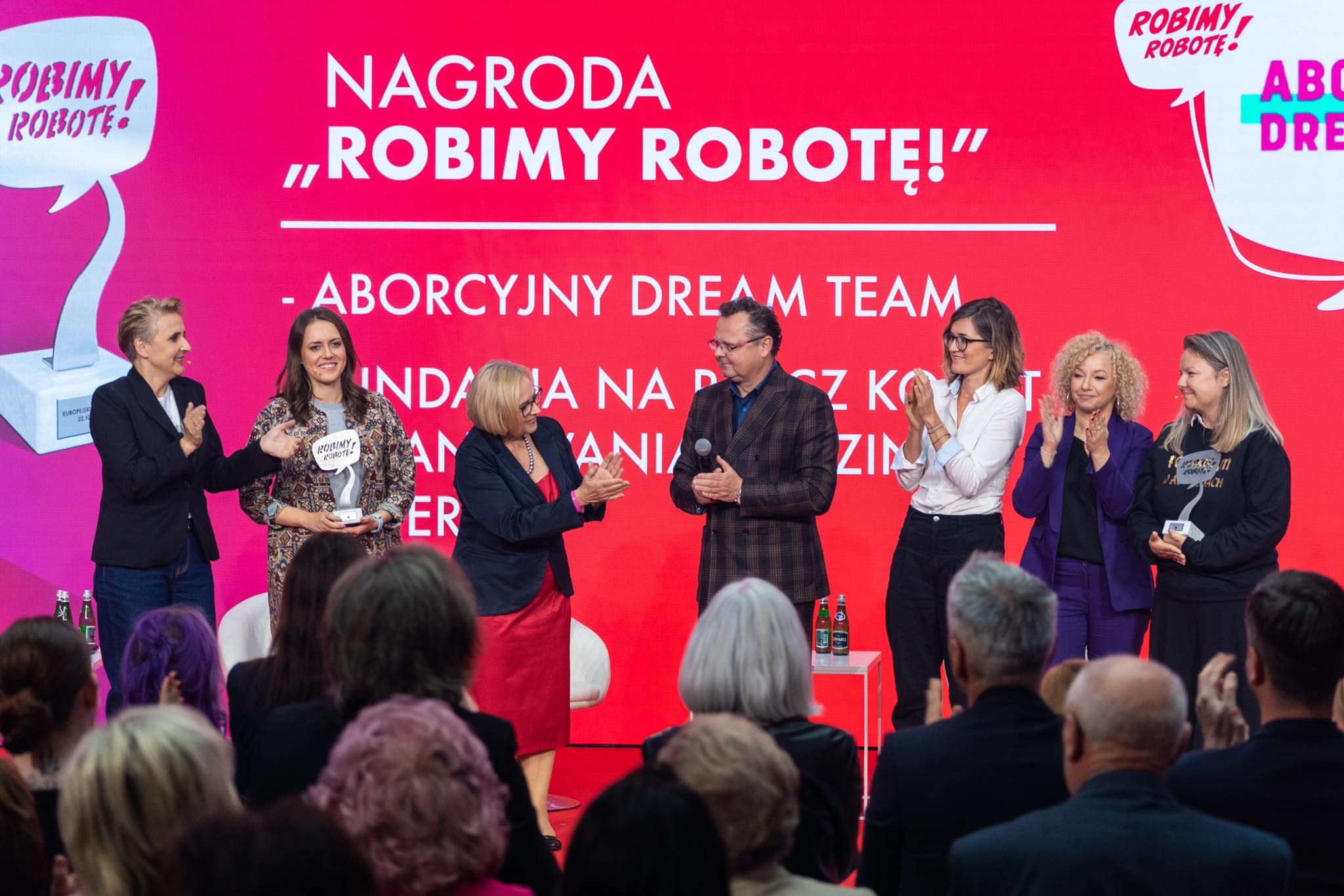 Na zdjęciu widać grupę ludzi biorących udział w ceremonii wręczenia nagrody