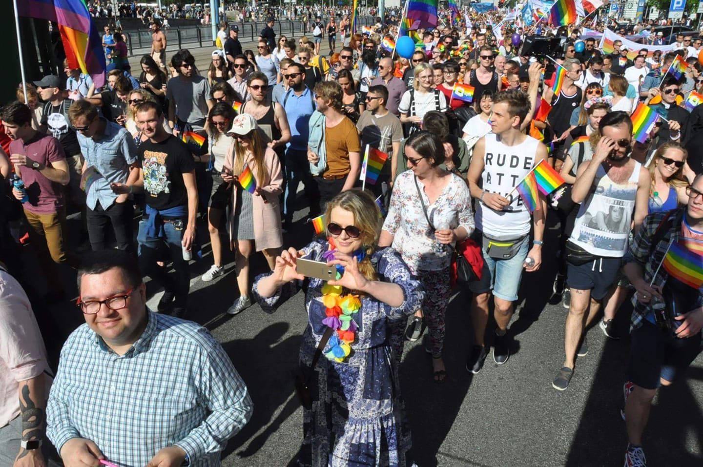 Uczestnicy 18. Parady Równości maszerują ulicami, trzymając tęczowe flagi i balony.