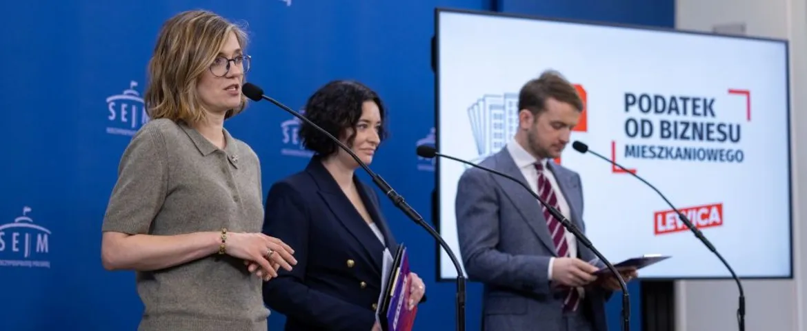 Trzy osoby stoją przy mikrofonach podczas konferencji prasowej, a na ekranie w tle widnieje napis „Podatek od Biznesu Mieszkaniowego” i logotyp Lewicy.