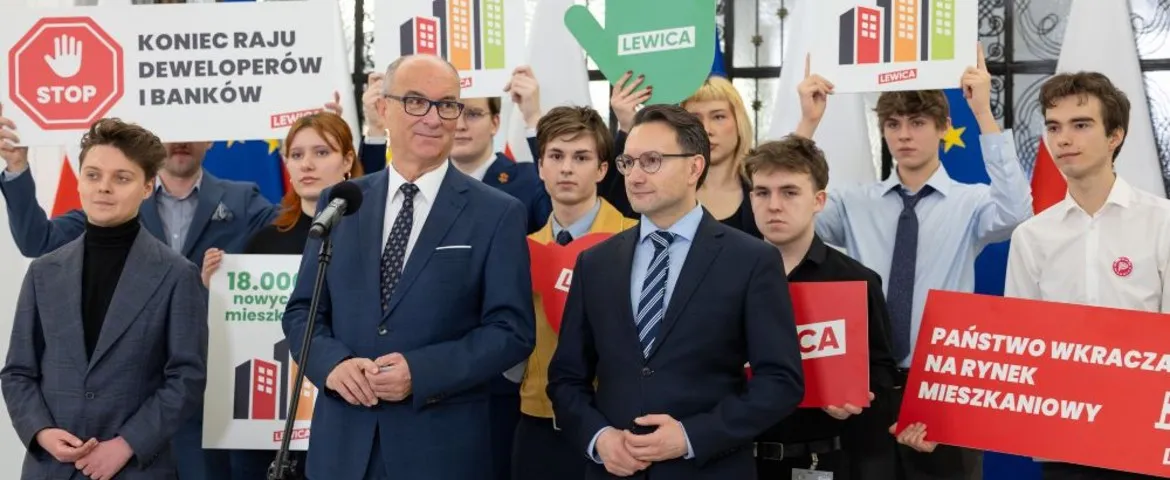 Grupa ludzi w garniturach na konferencji prasowej Lewicy, trzymają plakaty i banery z hasłami dotyczącymi rynku mieszkaniowego i deweloperów.